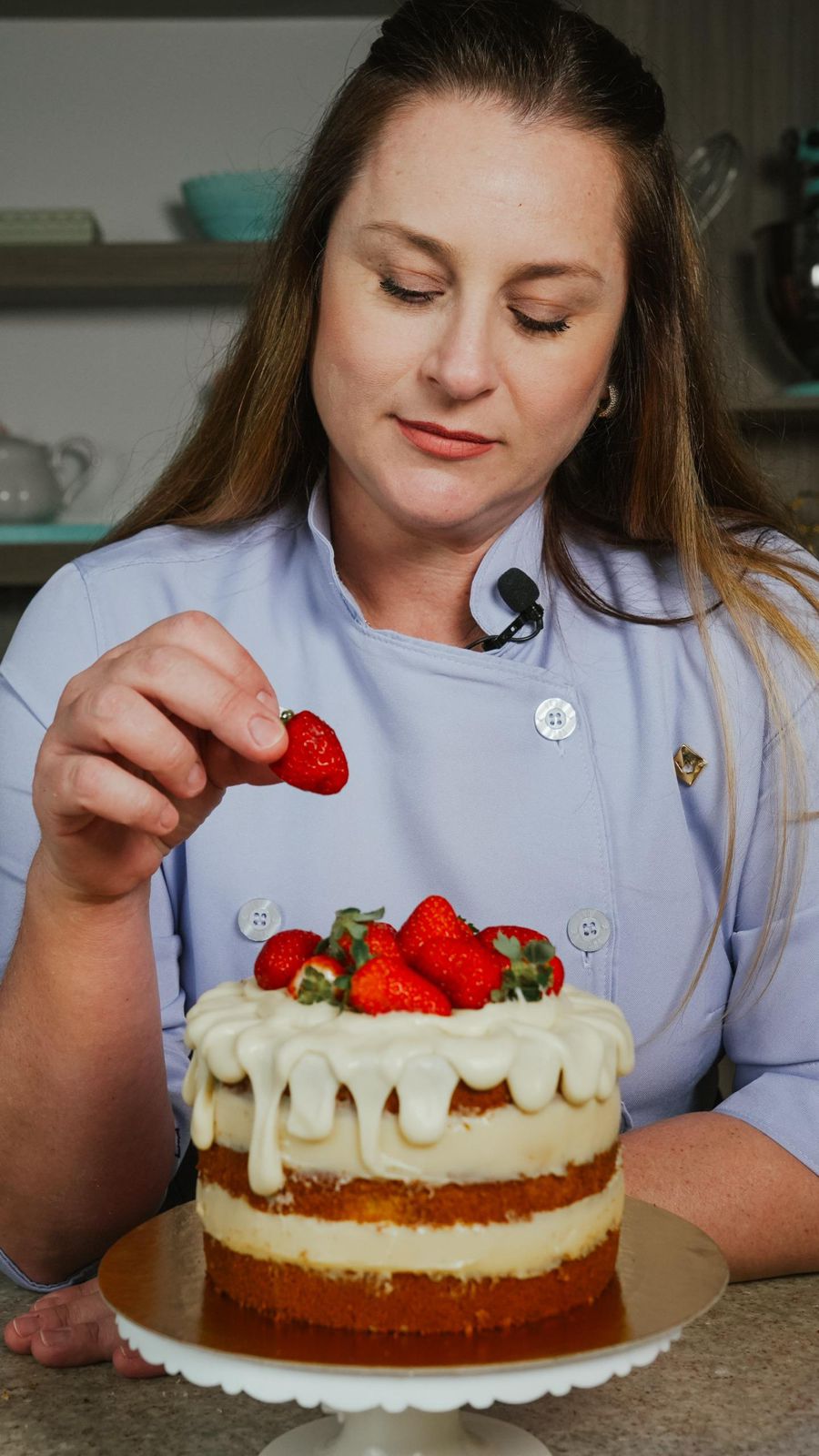 Chef Luana finalizando um naked cake com morangos